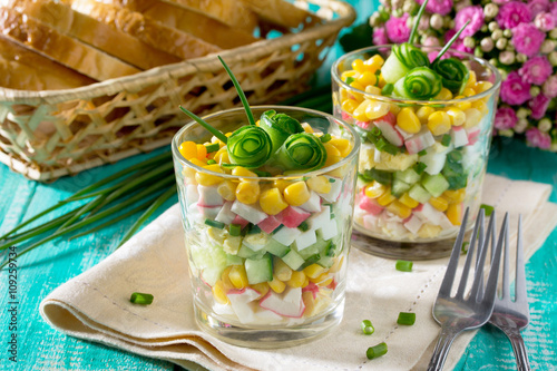 Salad with crab sticks, corn, cucumber and egg on a wooden table