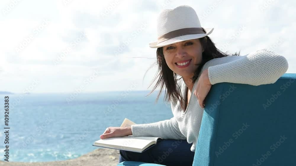 Woman reading book in armchair by the sea Woman reading book in armchair by the sea