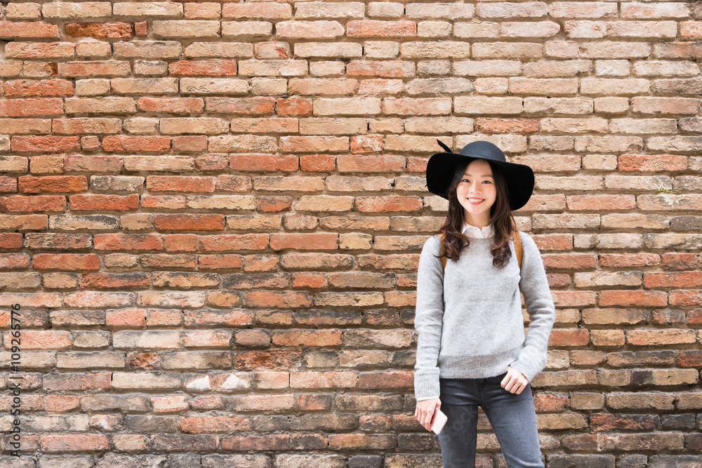 Beautiful asian girl in fashionable dress, standing in front of red brick wall background with copy space