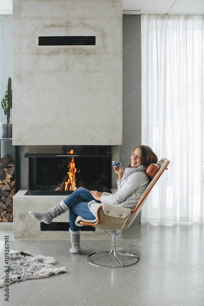 Woman drinking coffee in front of fireplace Woman drinking coffee in front of fireplace