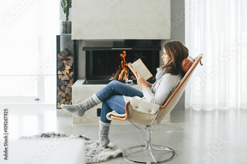 Woman reading book in front of fireplace photo