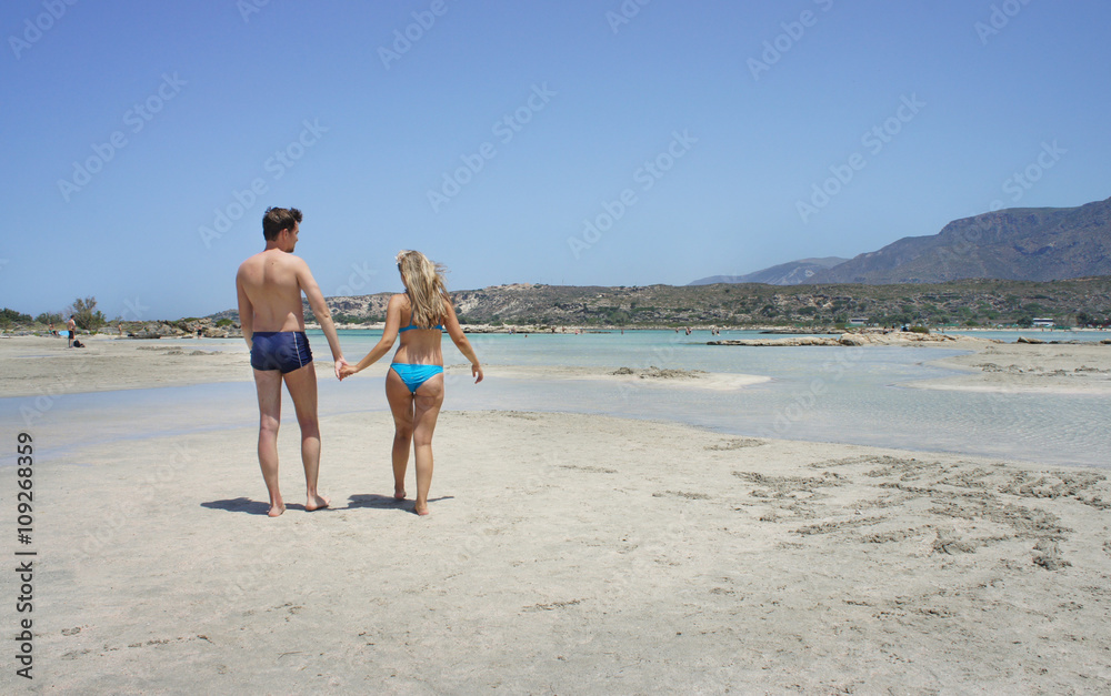 Beautiful young couple walking on the beach