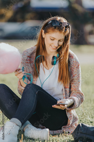 Cute caucasian young woman talking emotional and chat on the phone in the street near green park on spring sunset