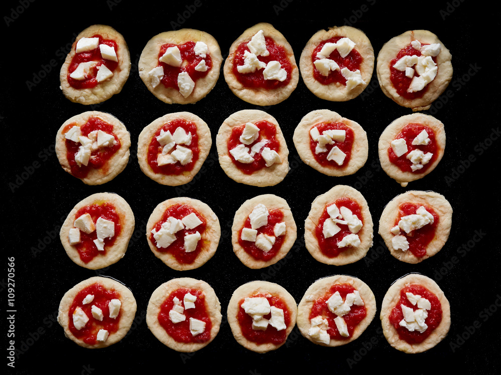 Small home made raw pizzas placed on a black surface Small home made raw pizzas placed on a black surface