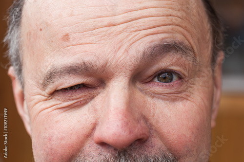 Elderly man with a mustache, winking with one eye