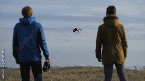 Two engineers watching the drone landing. Quadrocopters sits in automatic mode, 