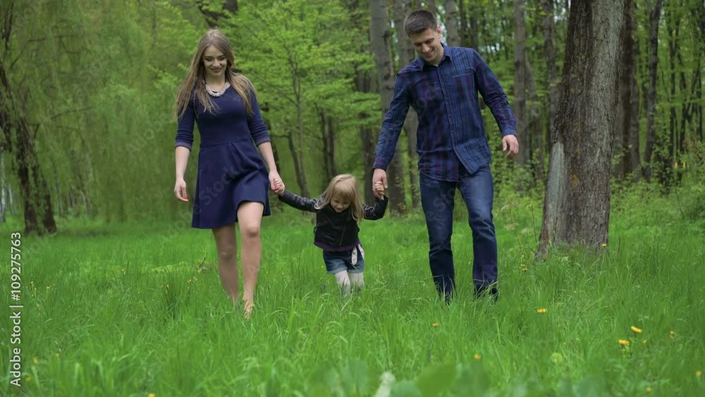 Young family with daughter walking on green grass in the park. 4k Young family with daughter walking on green grass in the park. 4k