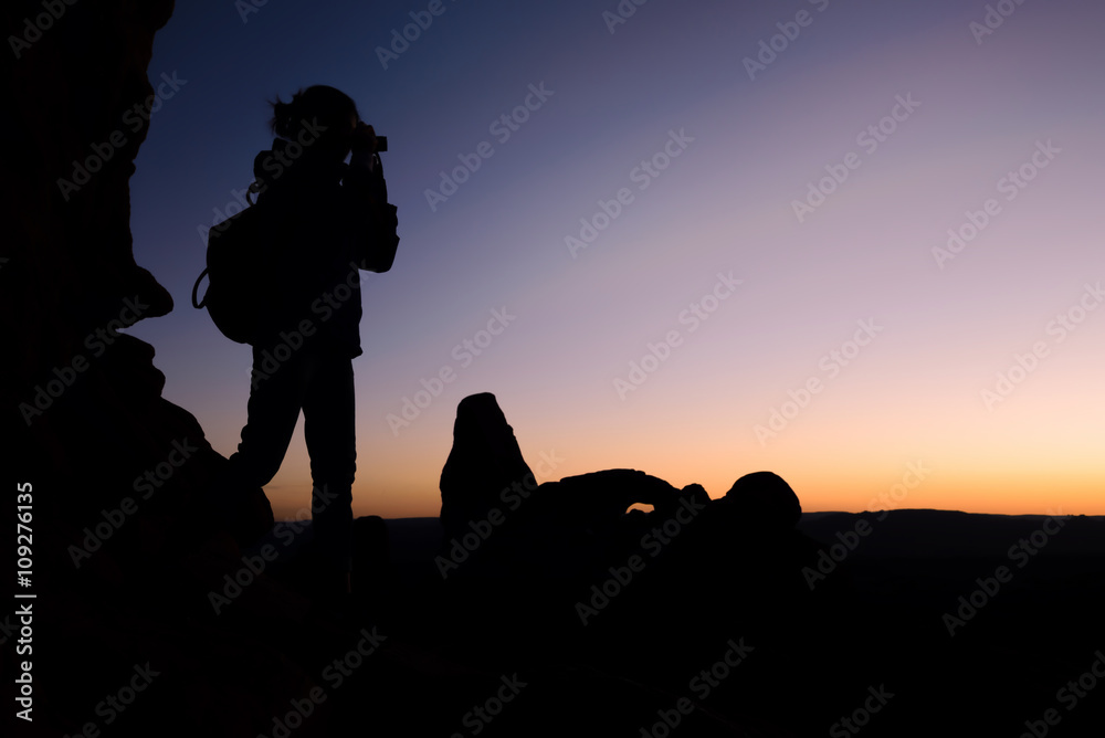 Silhouette of woman traveler shooting camera sunset