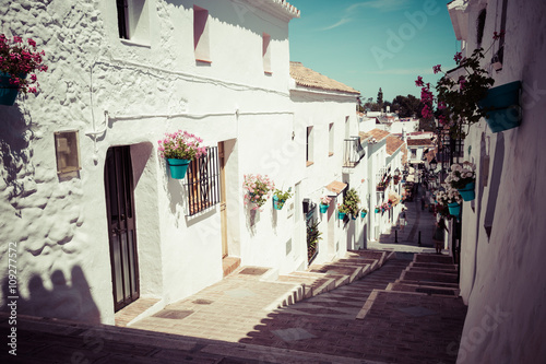 Cuadro en lienzo Picturesque street of Mijas with flower pots in facades. Andalus