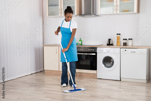 Female Janitor Mopping Floor In Kitchen