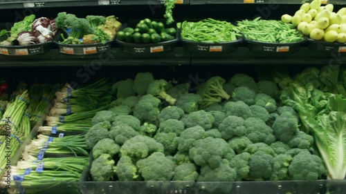 Medium tracking shot of vegetables in a grocery store