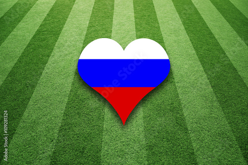 Sunny soccer artificial green grass field with Russia flag colors love heart symbol background.