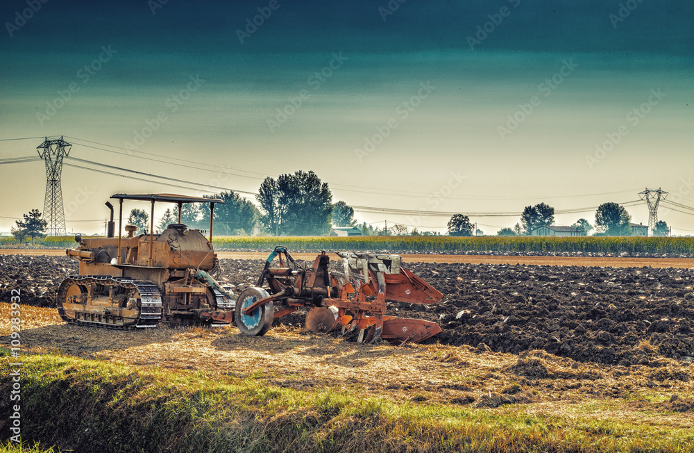 Obraz premium old tractor plowing a field