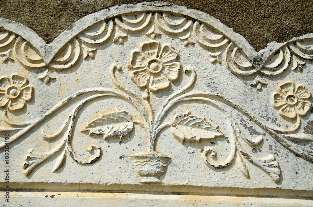Old sunlit flowery wall ornament