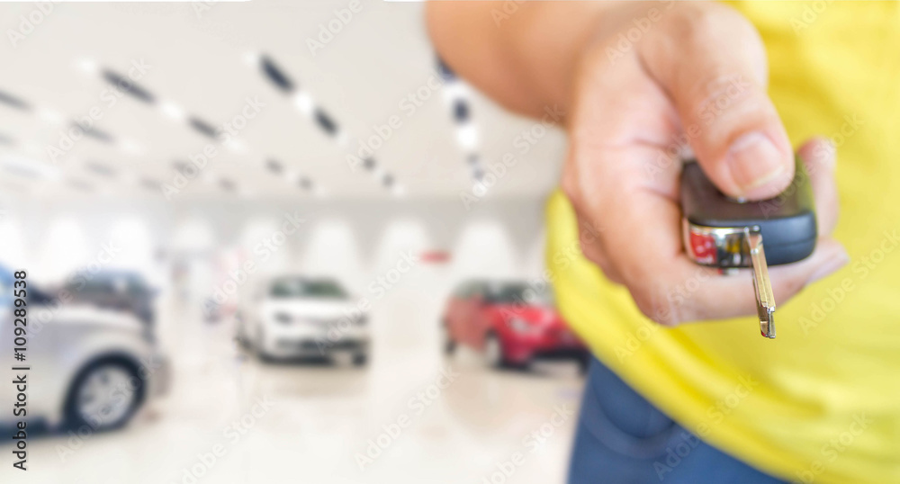 hand of man with car key on blur photo car showroom hand of man with car key on blur photo car showroom
