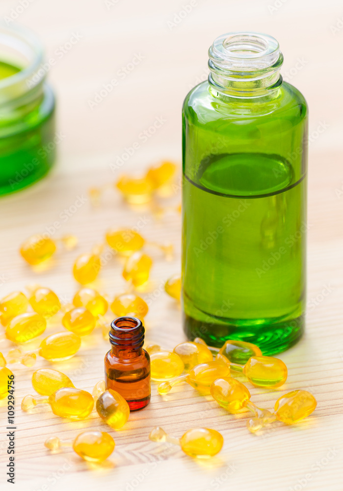 gold capsules of natural cosmetik for face and bottles with essential oils on the wooden background