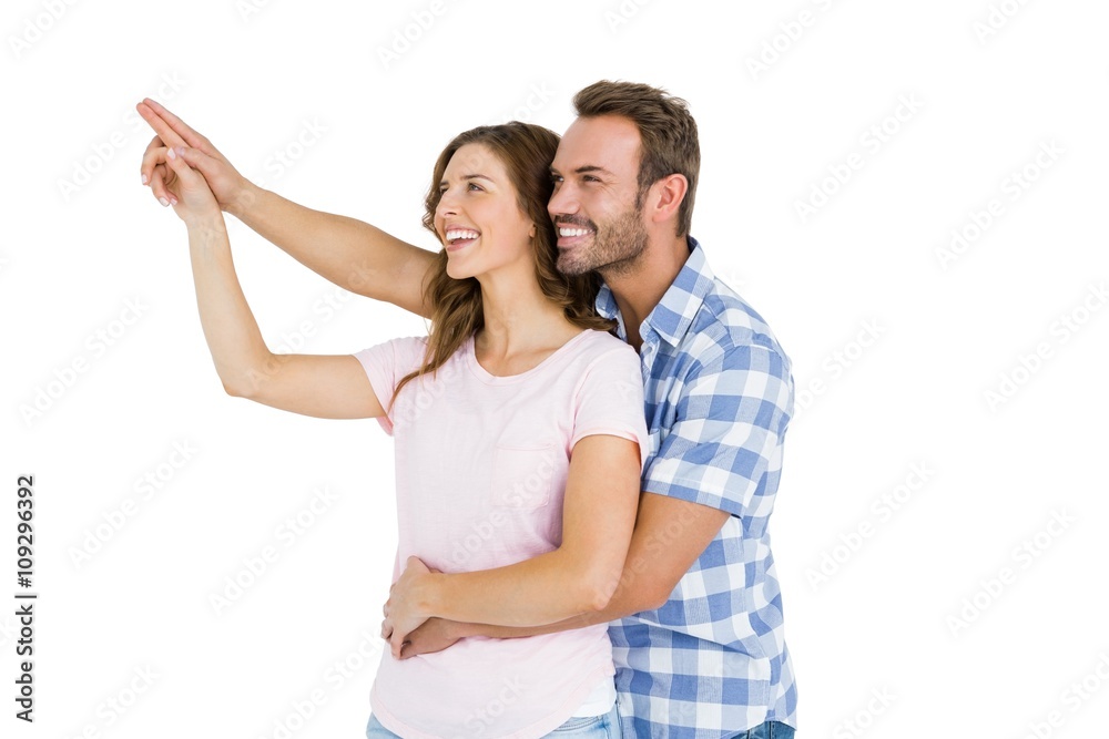 Happy young couple embracing and pointing upward Happy young couple embracing and pointing upward