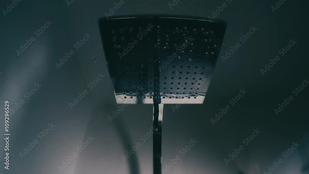 détail main d'homme ouvrant le robinet de la douche avec vue de l'eau qui coule de la tête
de douche