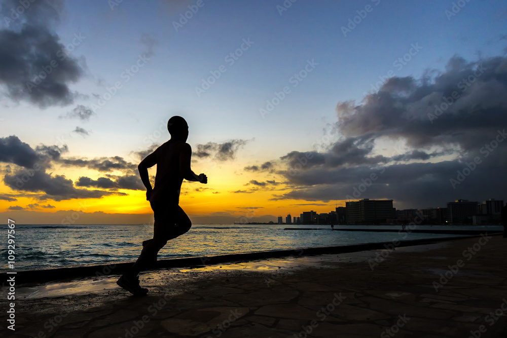 Silhoutte of runner jogging along Waikiki beach at sunset golden hour