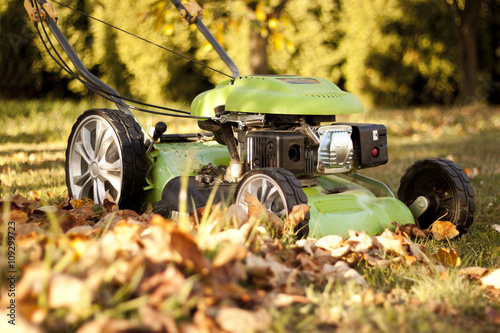 Obraz na plátně Green lawn mower in the garden at sunset