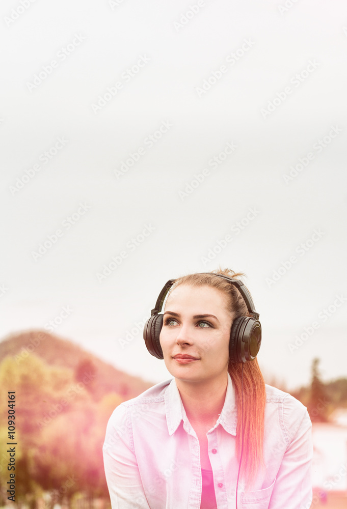 Attractive young girl enjoying music in a sunny day outside