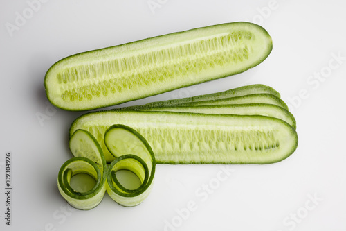 Sliced and rolled fresh cucumber on white background from above
