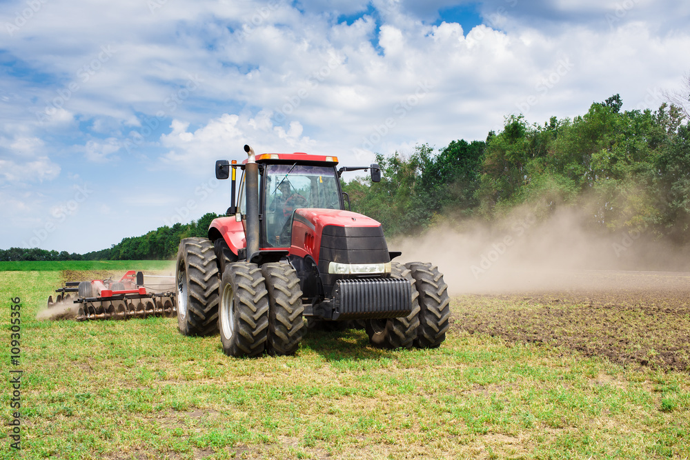 Modern tech red tractor plowing a green agricultural field in spring on the farm. Harvester sowing wheat. Modern tech red tractor plowing a green agricultural field in spring on the farm. Harvester sowing wheat.