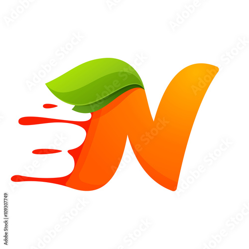 N letter with orange juice drops and leaves.