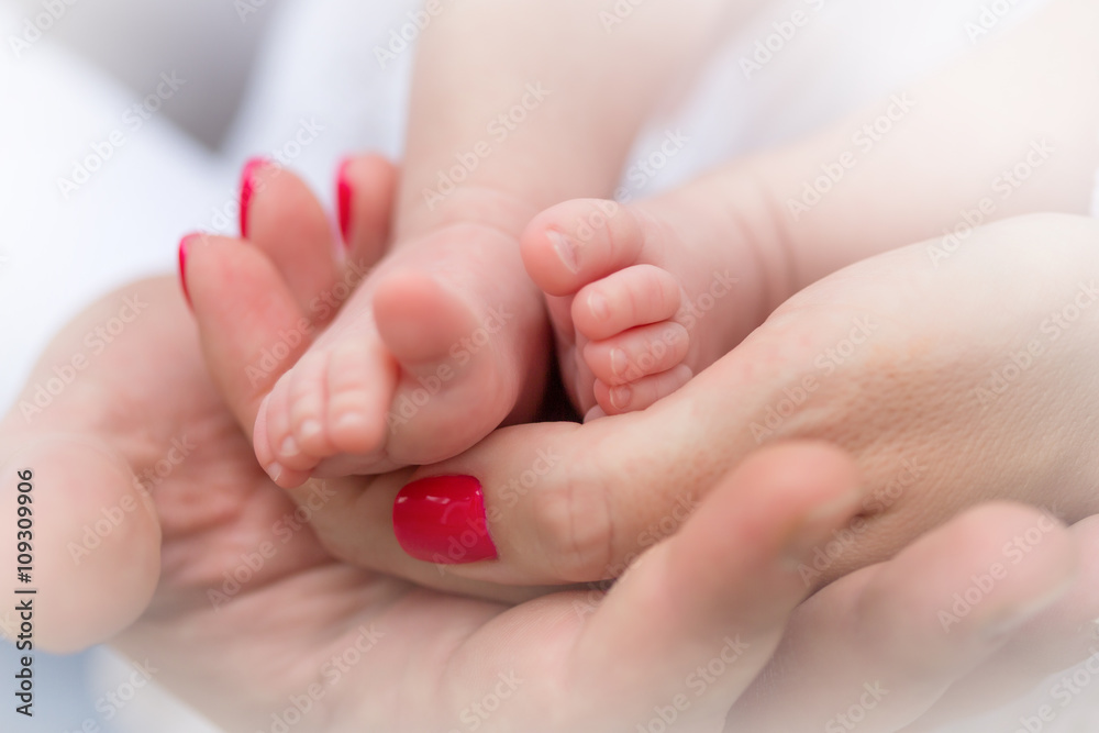 Mother holding tiny foot of newborn baby, close-up Mother holding tiny foot of newborn baby, close-up