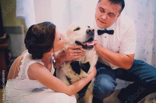 groom and bride playing with their dog labrador at home
