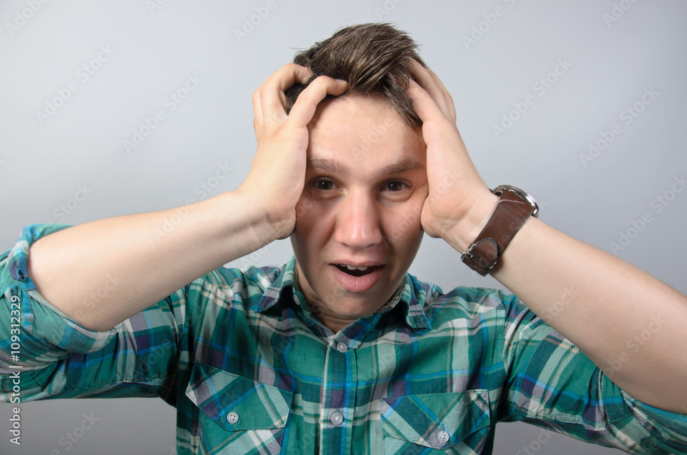 Portrait of frustrated shocked man in shirt standing against grey background