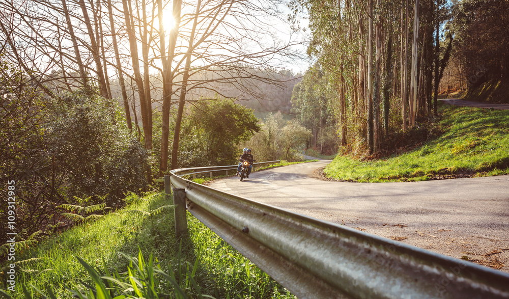 Obraz premium Senior couple riding motorbike along forest road