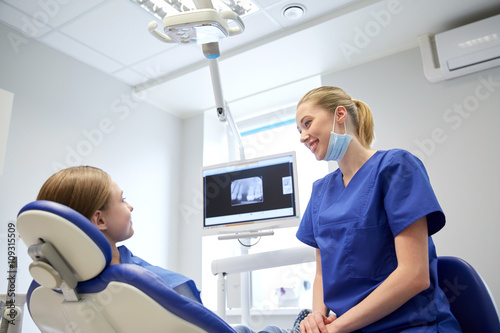 happy female dentist with patient girl at clinic