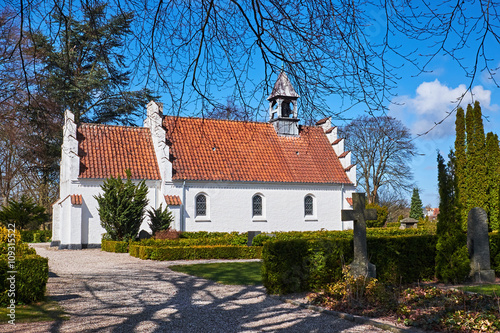 Classic white danish brick chapel with red clay layered roof tiles and a small bell tower