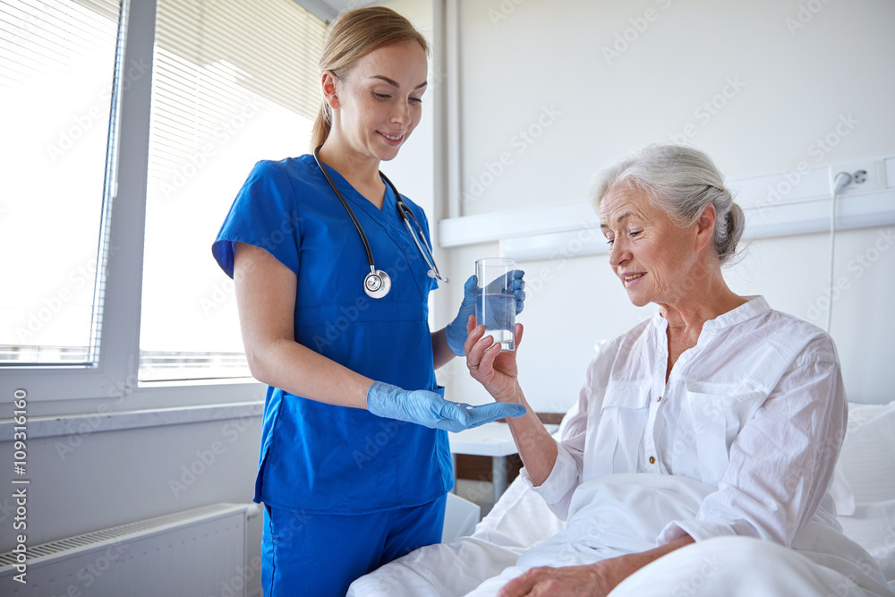 Obraz premium nurse giving medicine to senior woman at hospital