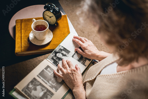 an elderly woman looks at your picture in the album made many years ago photo