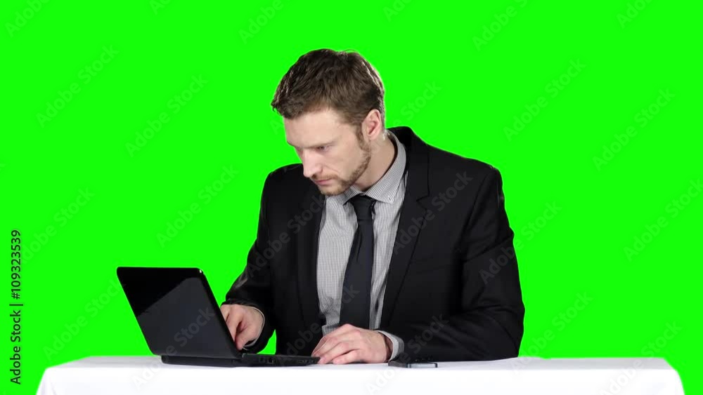 Businessman sitting at a desk and using notebook and calling on the phone. Green screen Businessman sitting at a desk and using notebook and calling on the phone. Green screen
