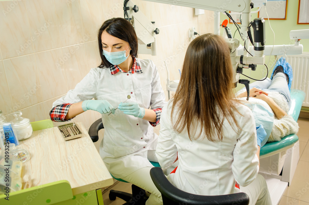 Dentist and assistant in a dental clinic, wearing masks and gloves