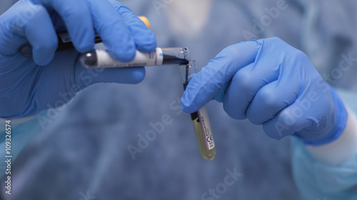Bild auf Leinwand The Laboratory Assistant is decanting a green liquid into a Test Tube with a yellow Liquid