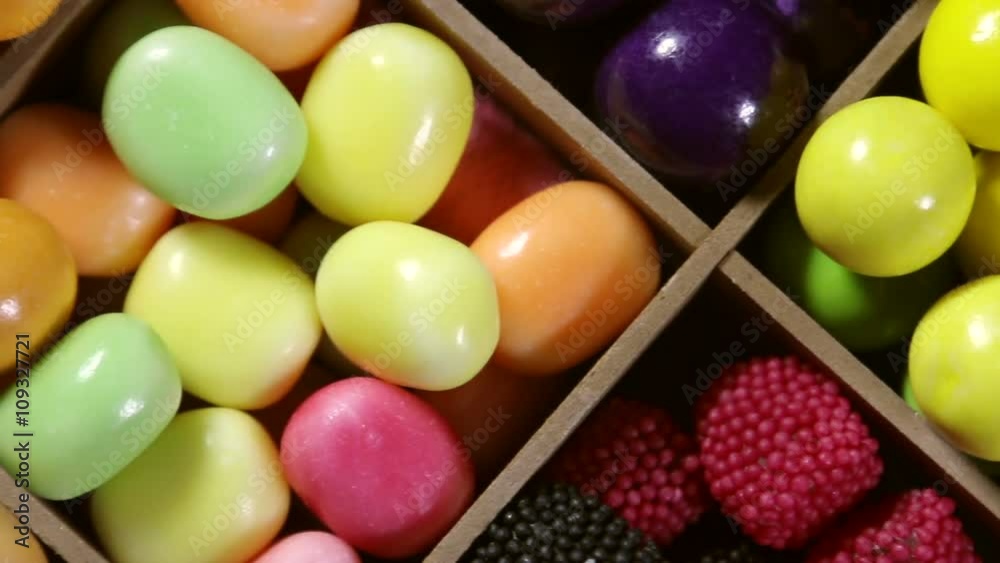 Multi-colored sweets, lollipops and chewing gum in a wooden box. dolly shot