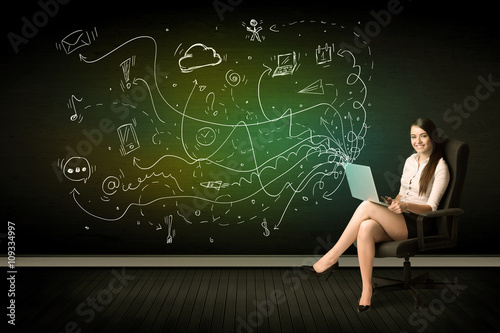 Businesswoman sitting in chair holding laptop with media icons