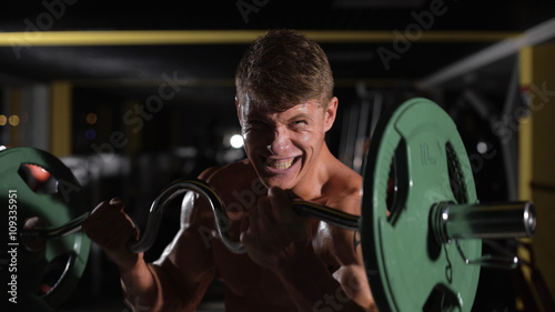 the last effort. of possibilities. Young adult bodybuilder doing weight lifting in gym.