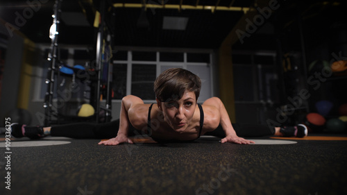 fitness, sport, training, gym and lifestyle concept - stretching young woman with earphones in the gym