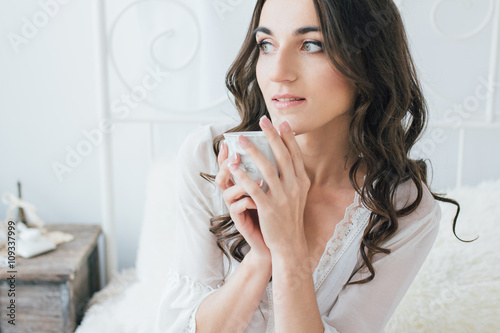 Beautiful young woman in white negligee in the morning