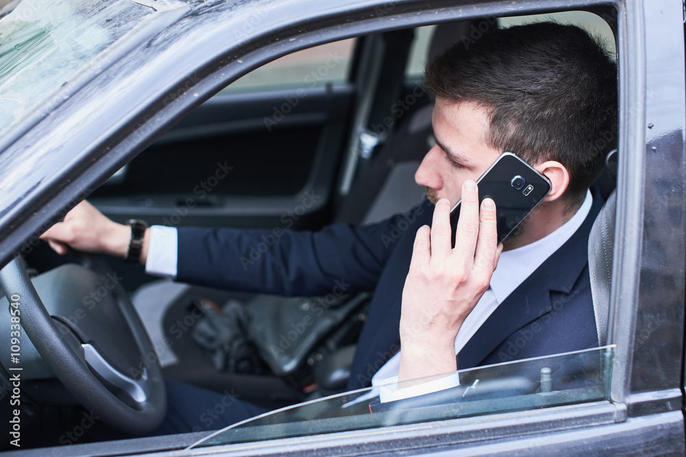 The guy in the suit sitting behind the wheel of a car and talking on a cell phone The guy in the suit sitting behind the wheel of a car and talking on a cell phone