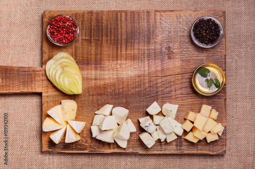 Cheese platter garnished with honey, apple and spice on rustic w