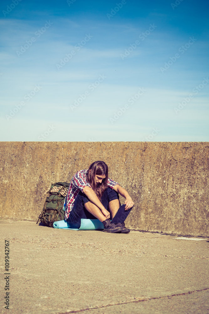 Man tourist backpacker sitting with tablet outdoor