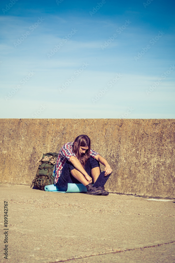 Fototapeta premium Man tourist backpacker sitting with tablet outdoor