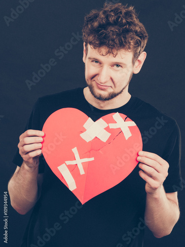 Sad man with glued heart by plaster. photo