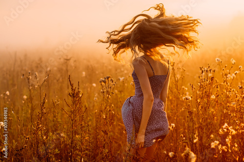 Obraz na płótnie Dancing beautiful girl in fog, field, sun backlight, sunrise, orange colors